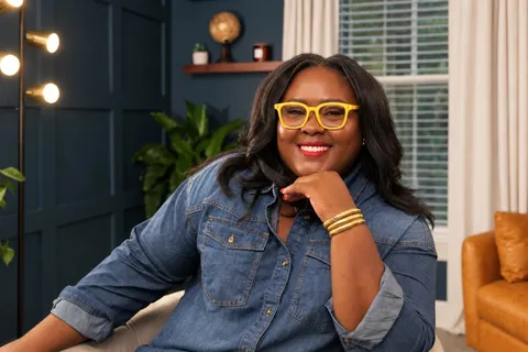 Ona smiling in a denim shirt and yellow glasses