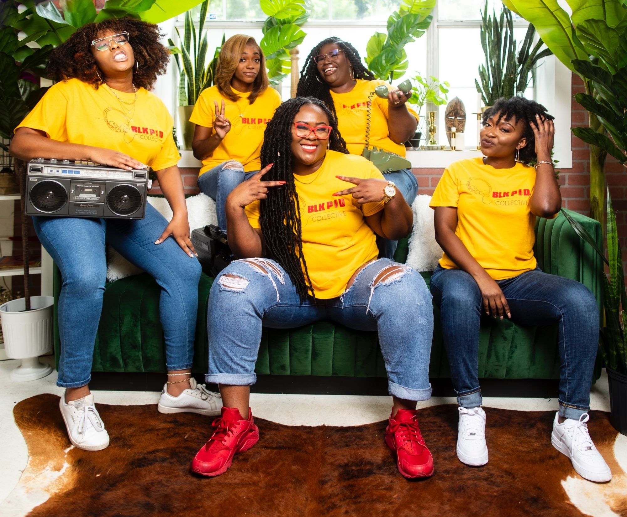 Ona with the Blk Pod Collective team in matching yellow shirts on a green couch